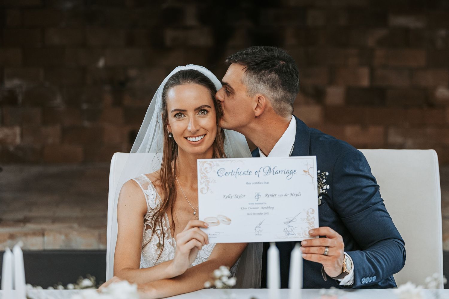 Newlyweds share a joyful moment while holding their marriage certificate.