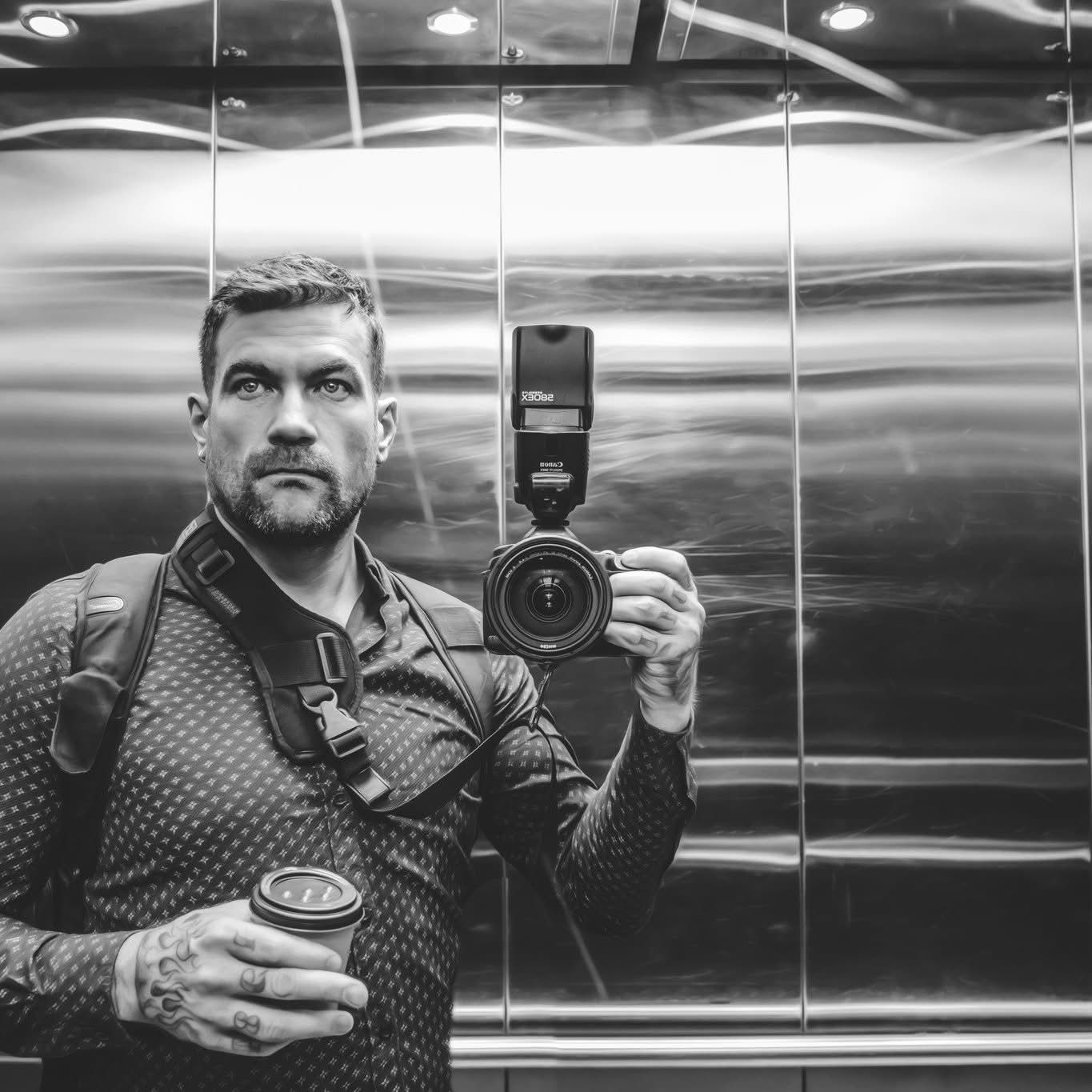 Black and white portrait series of photographer with camera equipment in elevator setting.