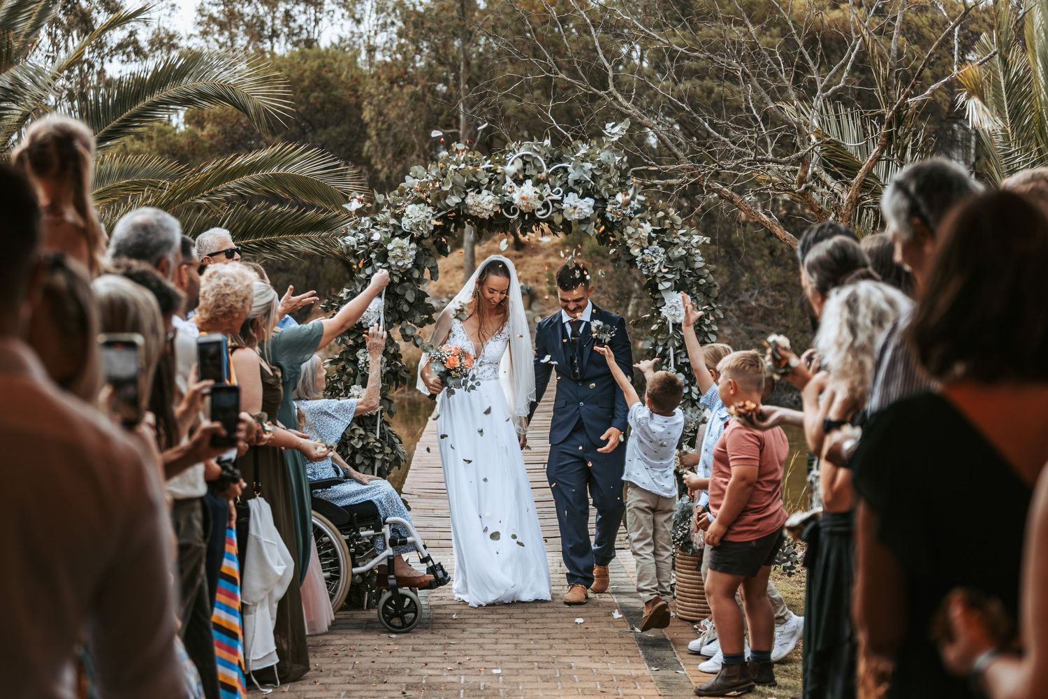 Guests form an aisle outdoors to celebrate the wedding couple.