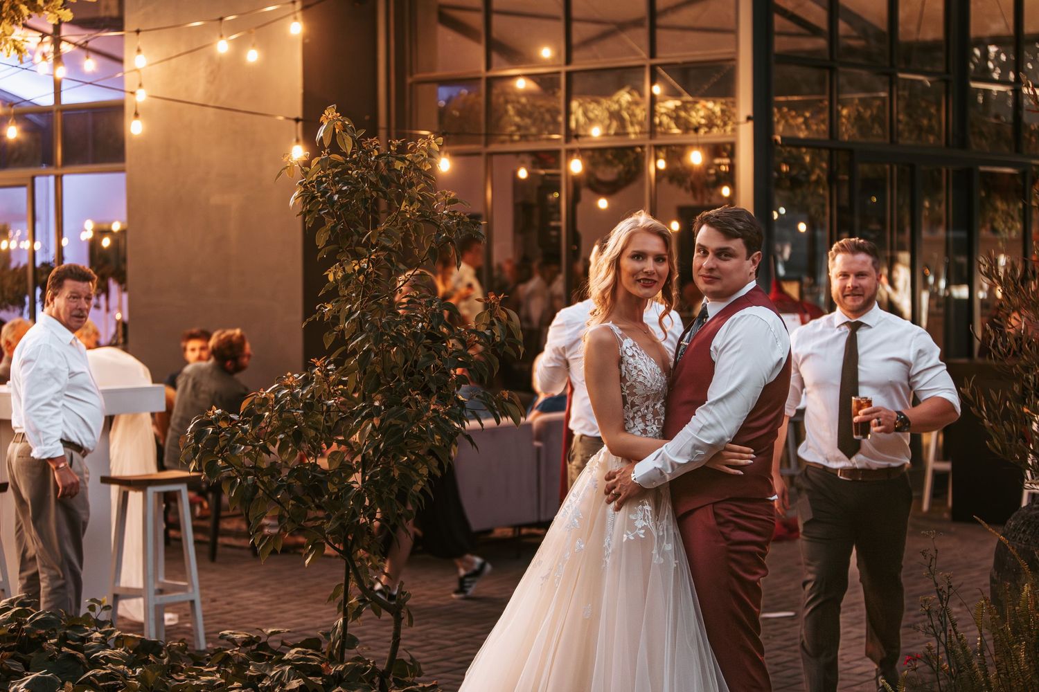 Wedding reception scene with string lights creating a warm ambiance in an outdoor venue.