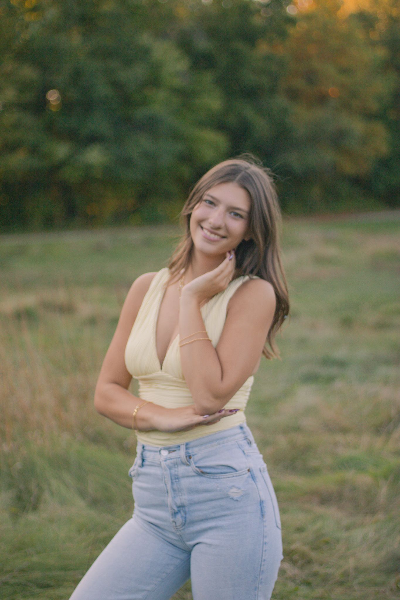 Casual outdoor photoshoot in yellow top and light denim in sunlit field during her senior photos at the Ledges in CVNP