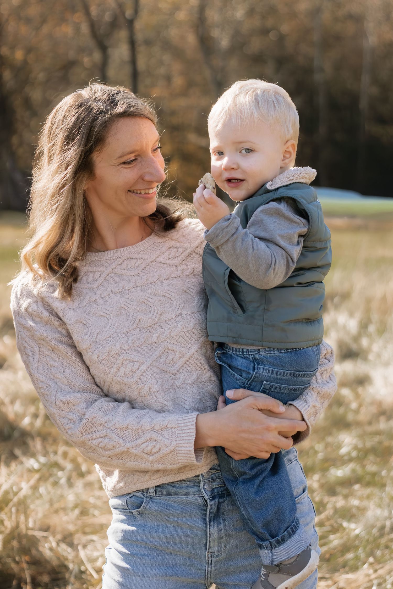 Mother and child sharing tender moment in sunlit autumn field.