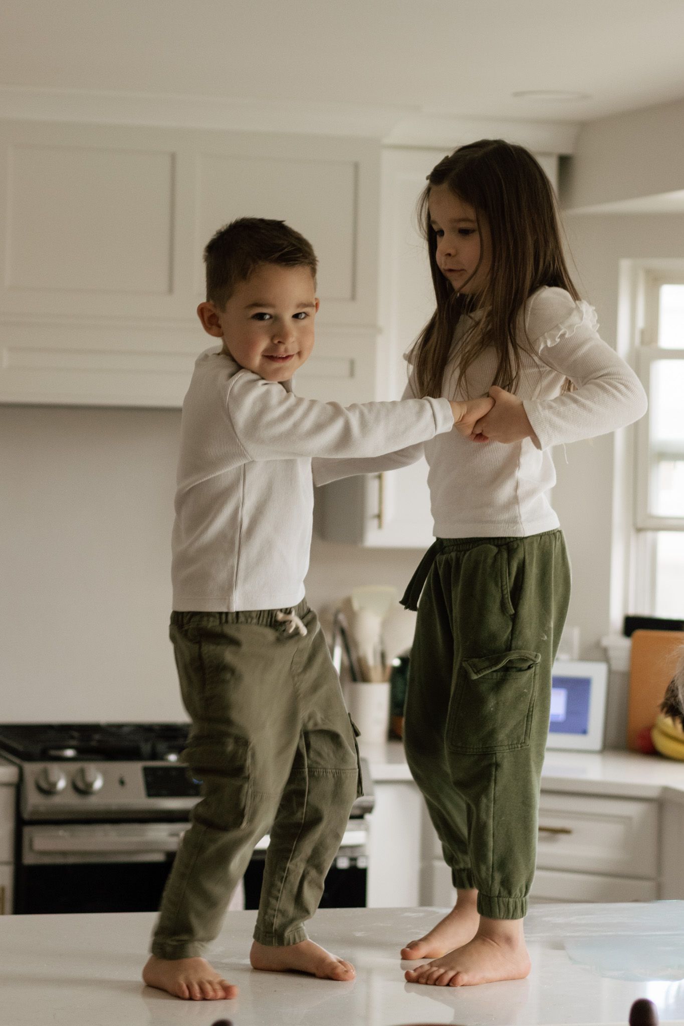 Two people in matching outfits dancing together on kitchen counter during their in home family photo session in Hudson, OH