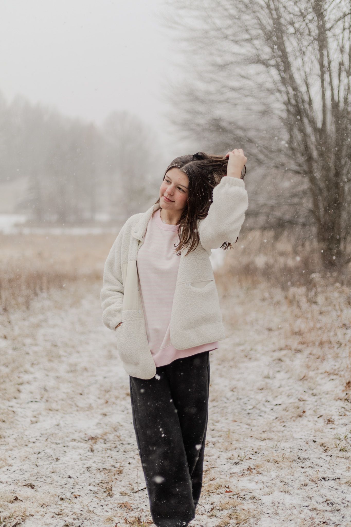 Winter portrait session in snowy field wearing cream colored jacket.