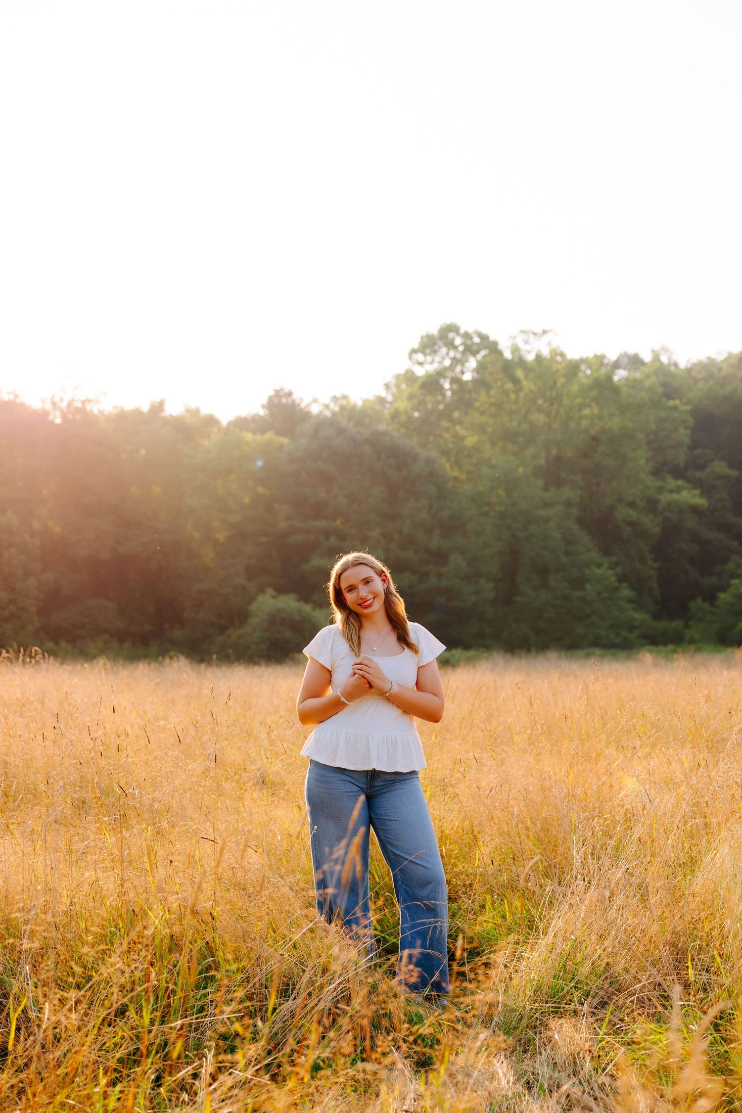 Golden hour photography in a meadow showing casual poses among tall grass at sunset.