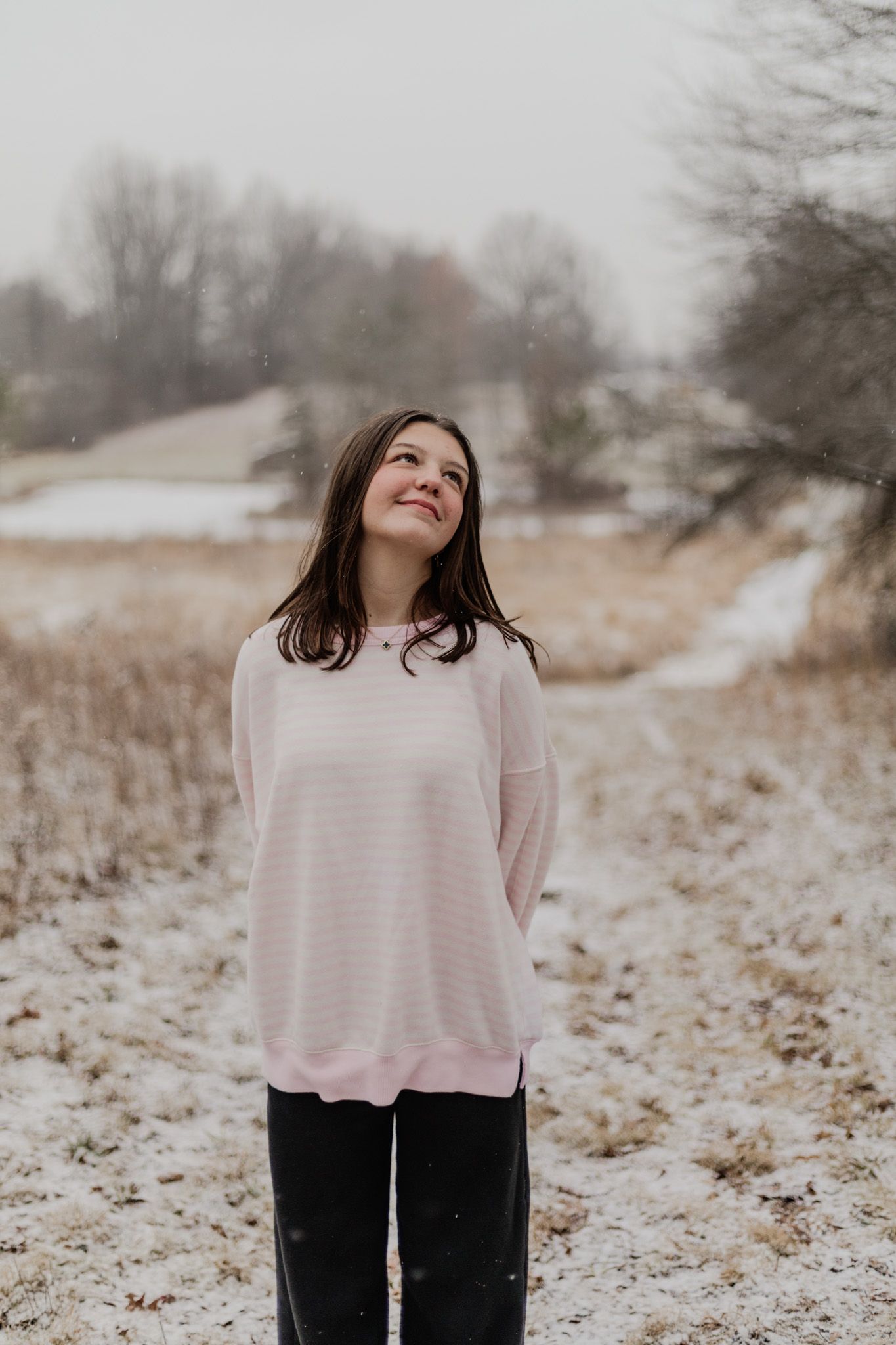 Winter portrait series in a snowy field wearing light colored sweater.