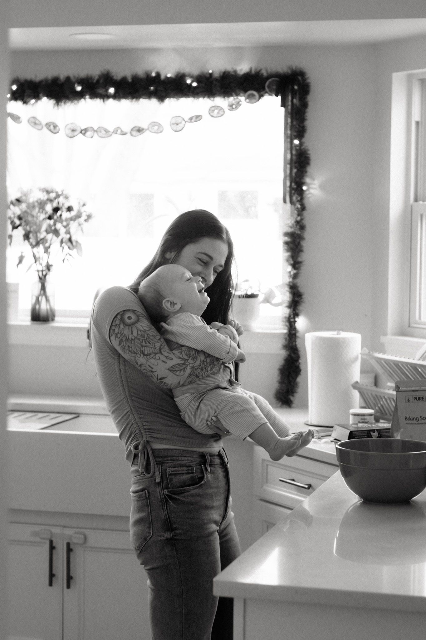 Black and white candid moment between two people in a modern kitchen.
