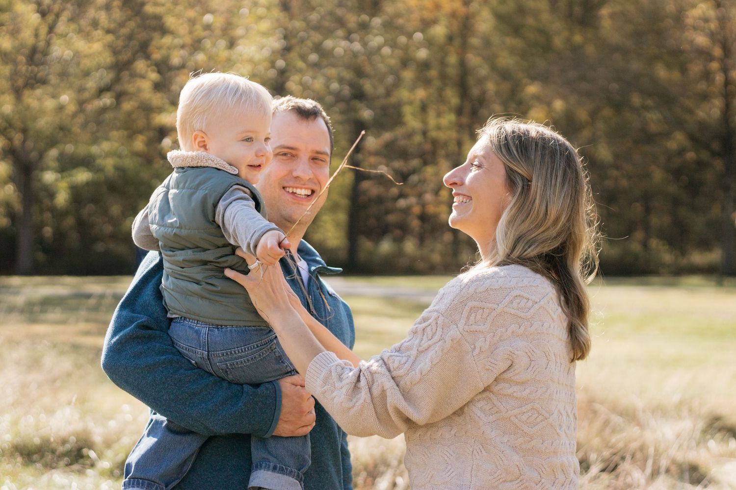 Family sharing joyful moment together in sunny autumn field during a family photoshoot in a grassy field in Brecksville, OH