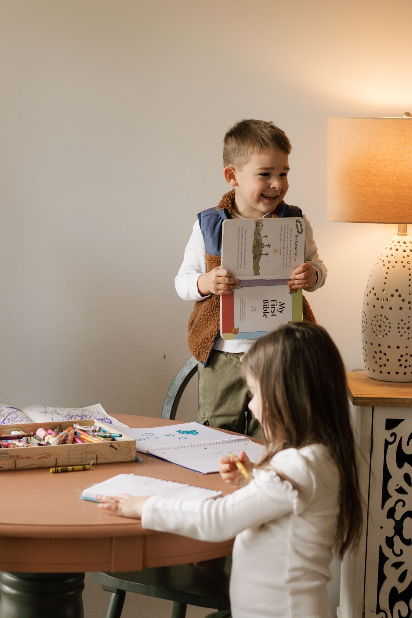 Two children sit at a table working on arts and crafts projects together during their in home family session in Akron, OH