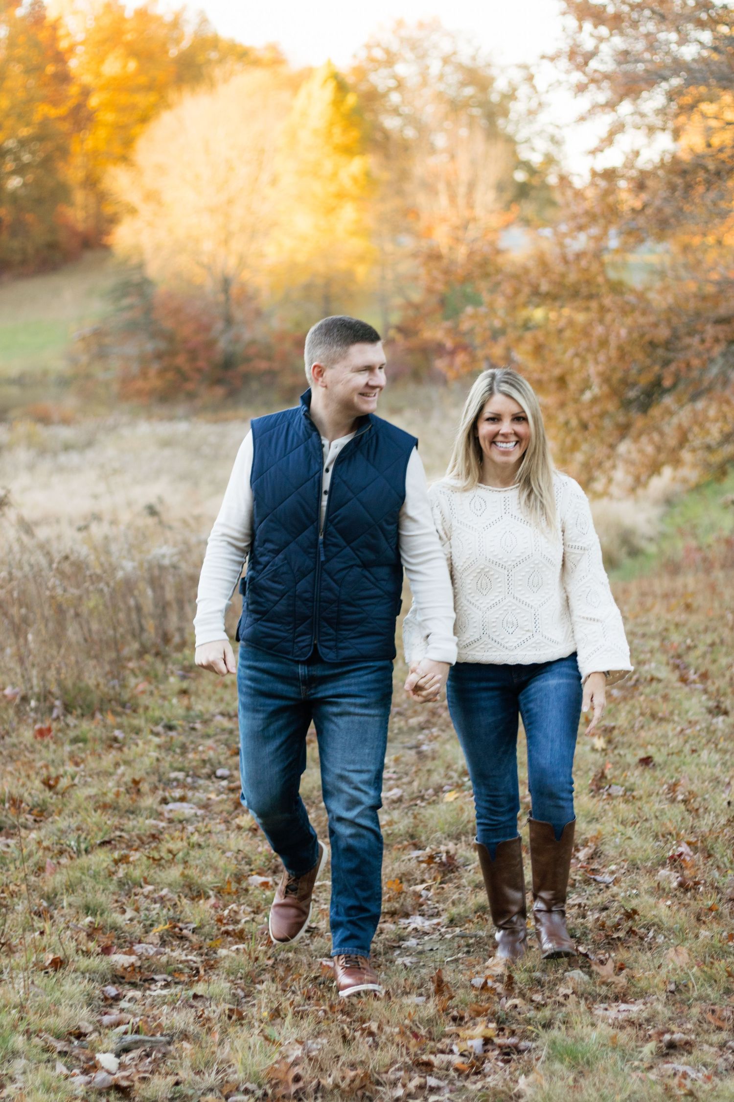 A couple walking together through autumn foliage wearing casual fall attire during their couples photo session in Hudson, OH
