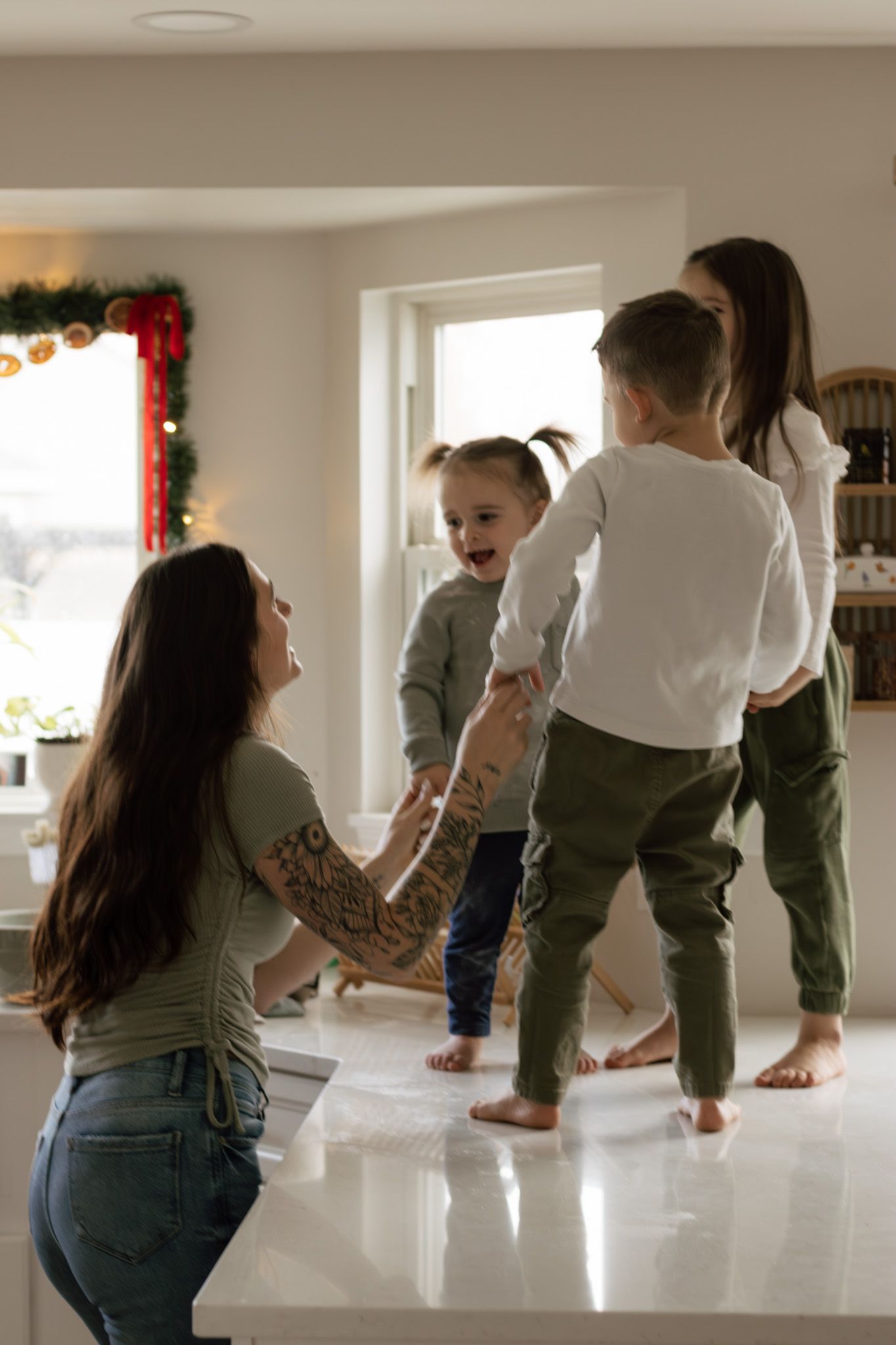 Playful family moment in bright kitchen with barefoot dancing and laughter.