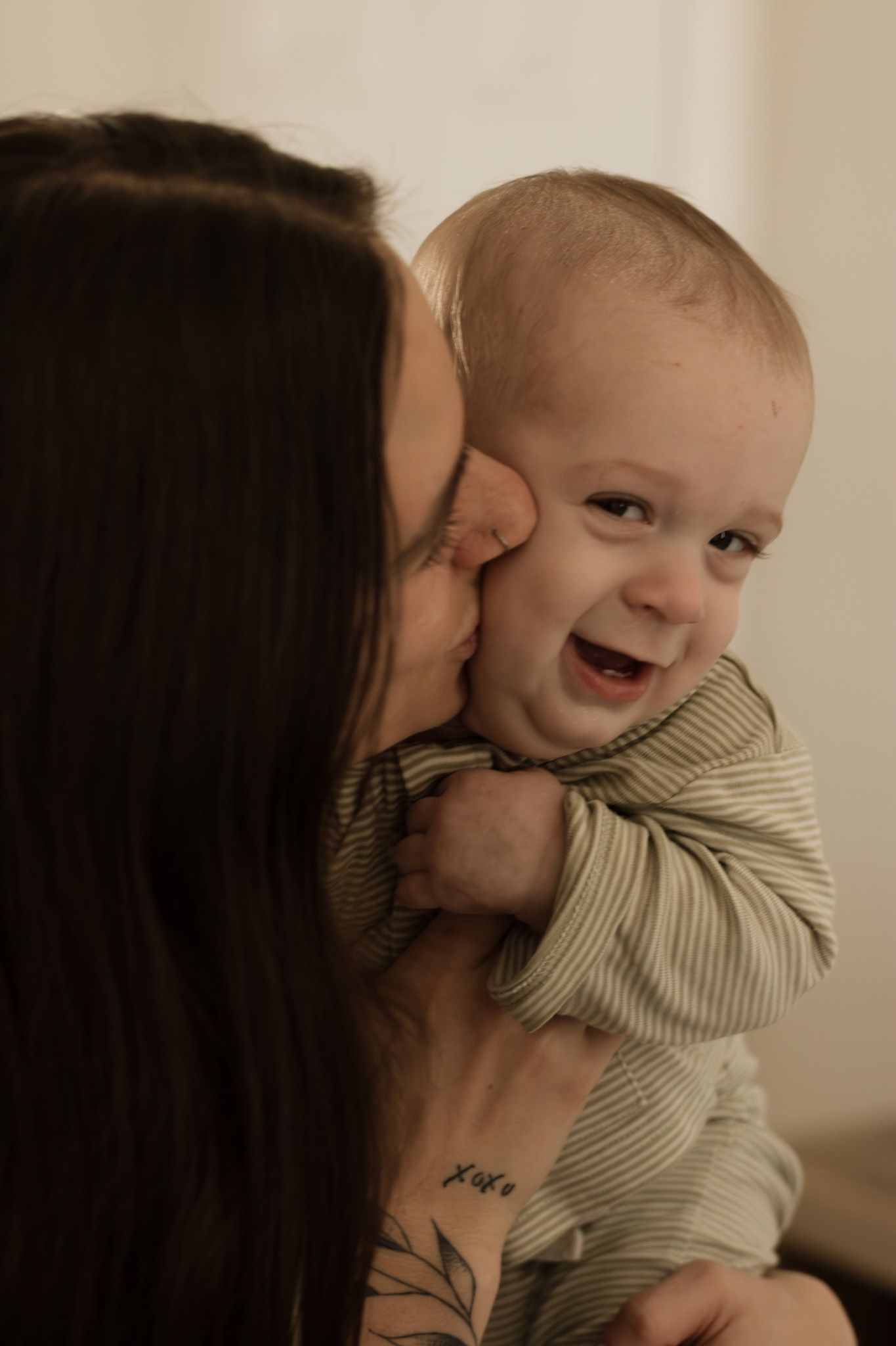 Tender moment between parent and baby sharing laughter and cuddles indoors.