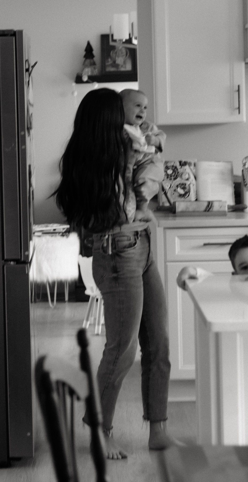 A tender moment in a kitchen with a baby being held up high during their in home family photo session in Akron, OH
