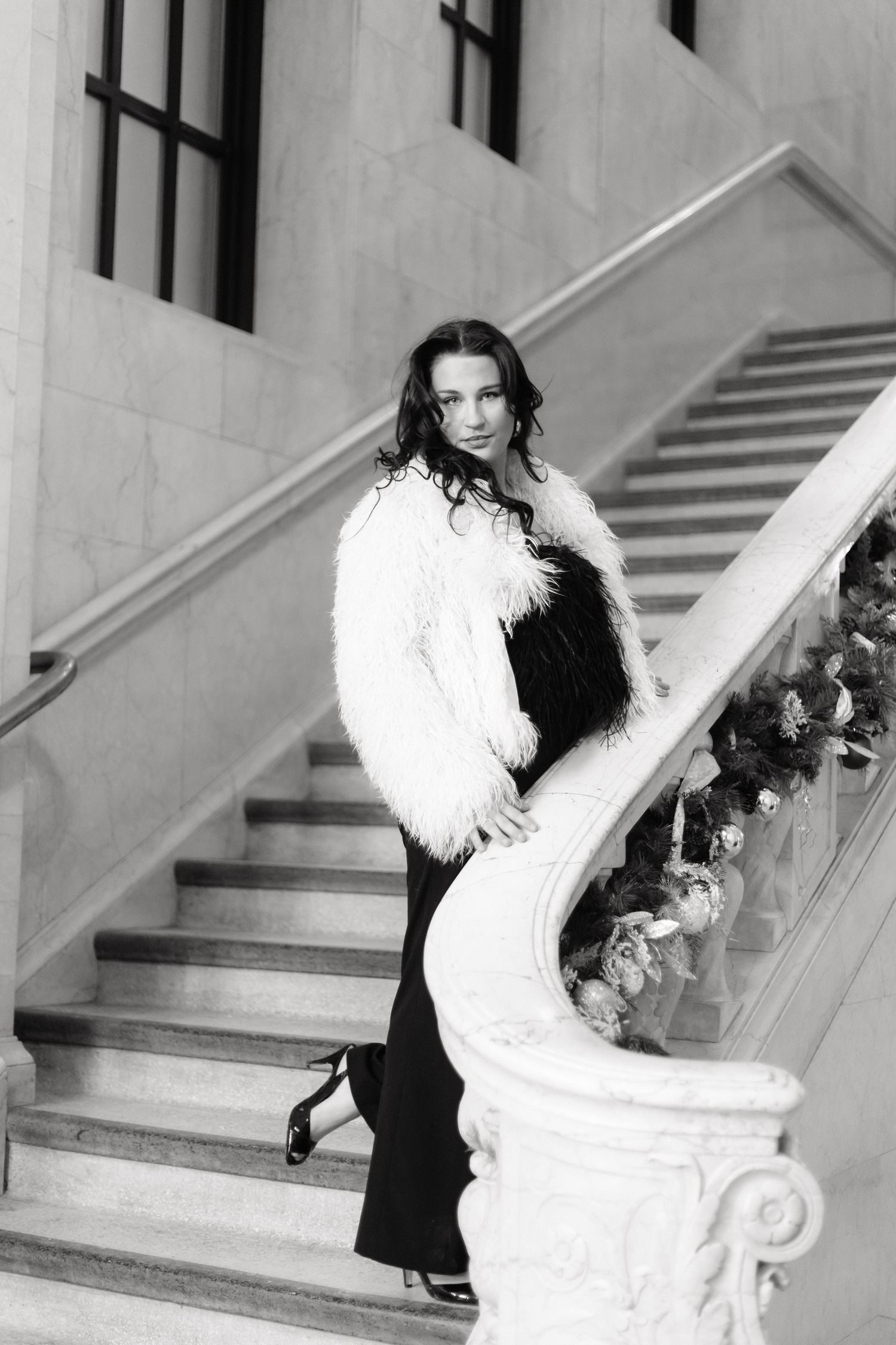 Black and white fashion portrait on elegant marble staircase with fur coat during her senior photos at Cleveland Public Library