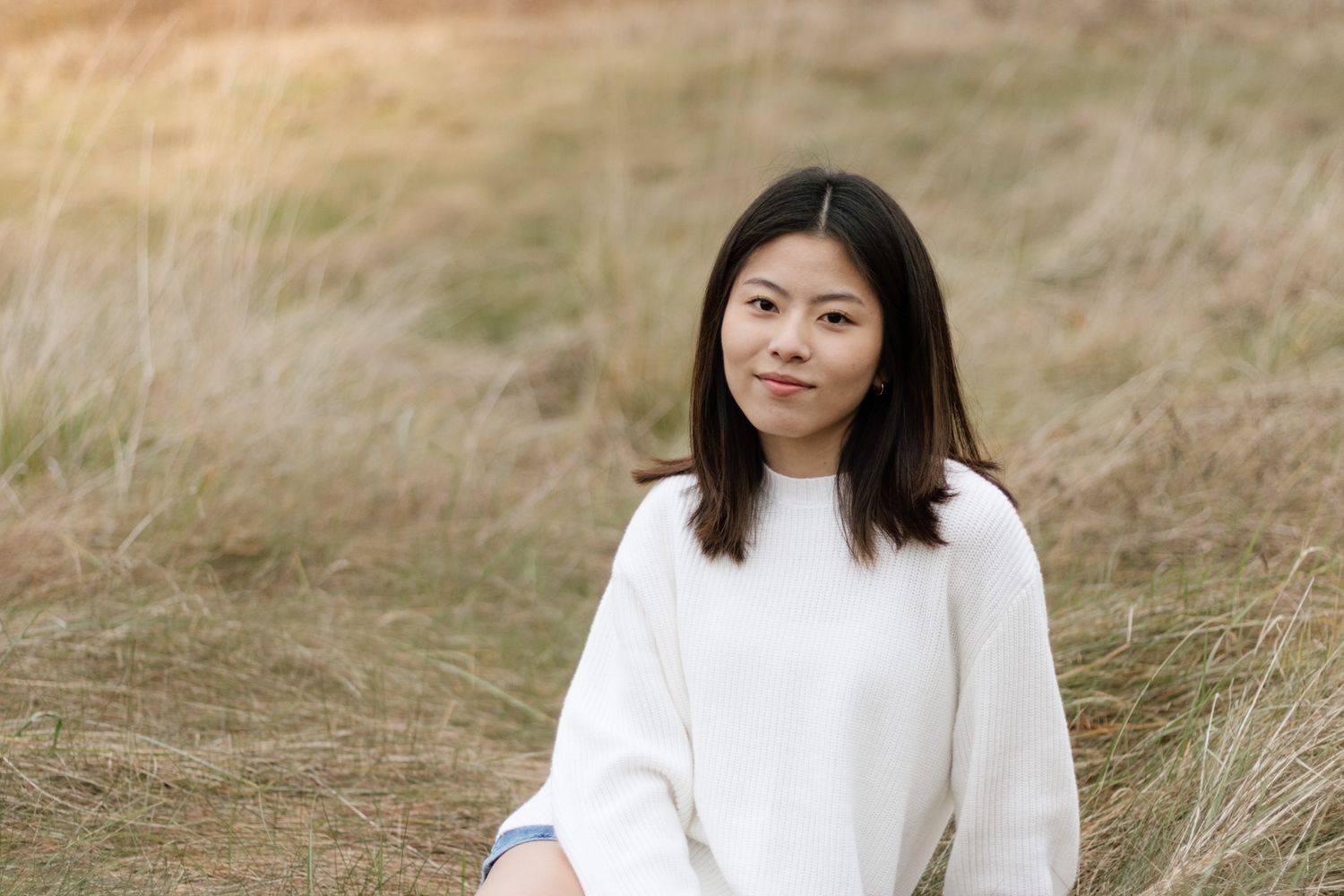 Outdoor portrait series featuring someone in a white sweater against a natural grassland background.