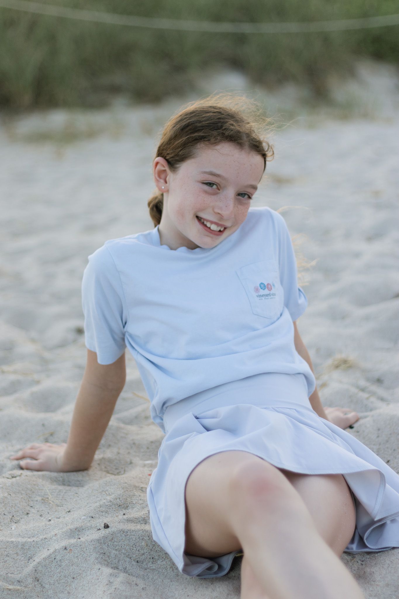 Relaxed beach poses showing someone lounging and playing in the sand while wearing a light blue outfit.