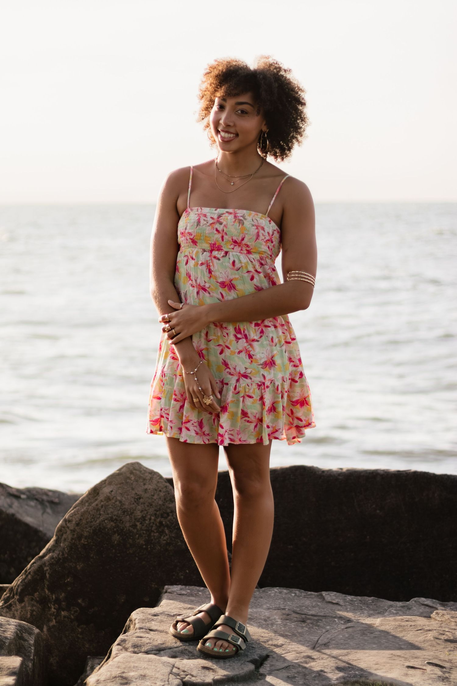 Playful beach portraits featuring a floral swimsuit against rocky coastal background.