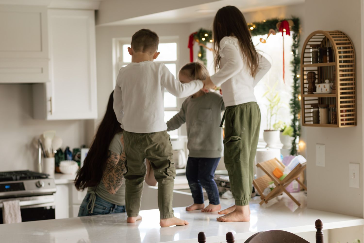 Candid kitchen scene showing family members cooking and interacting together in a bright white kitchen.