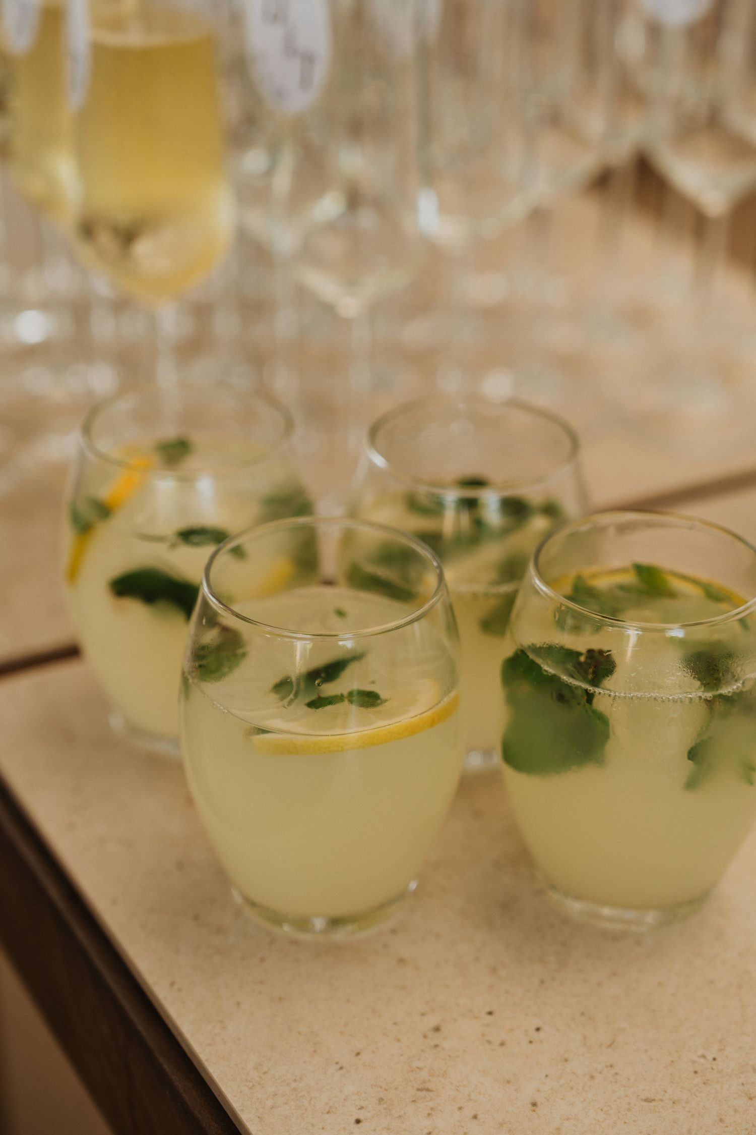 Refreshing citrus cocktails garnished with fresh herbs and lemon slices served on a wooden tray.