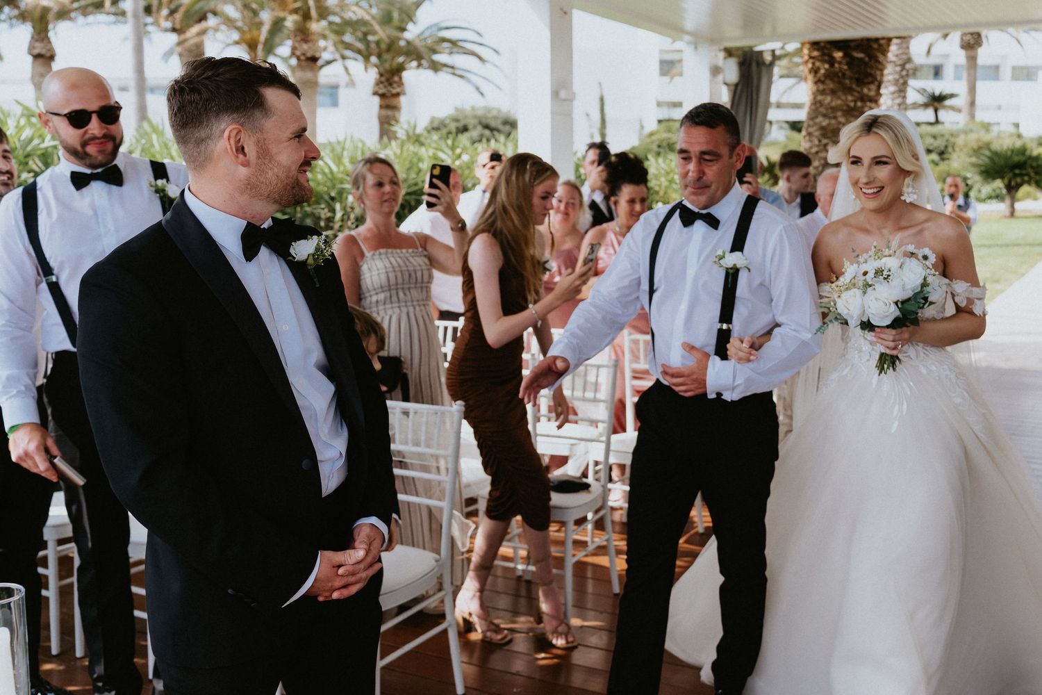 Wedding celebration on covered outdoor patio with formal attire and white decor.