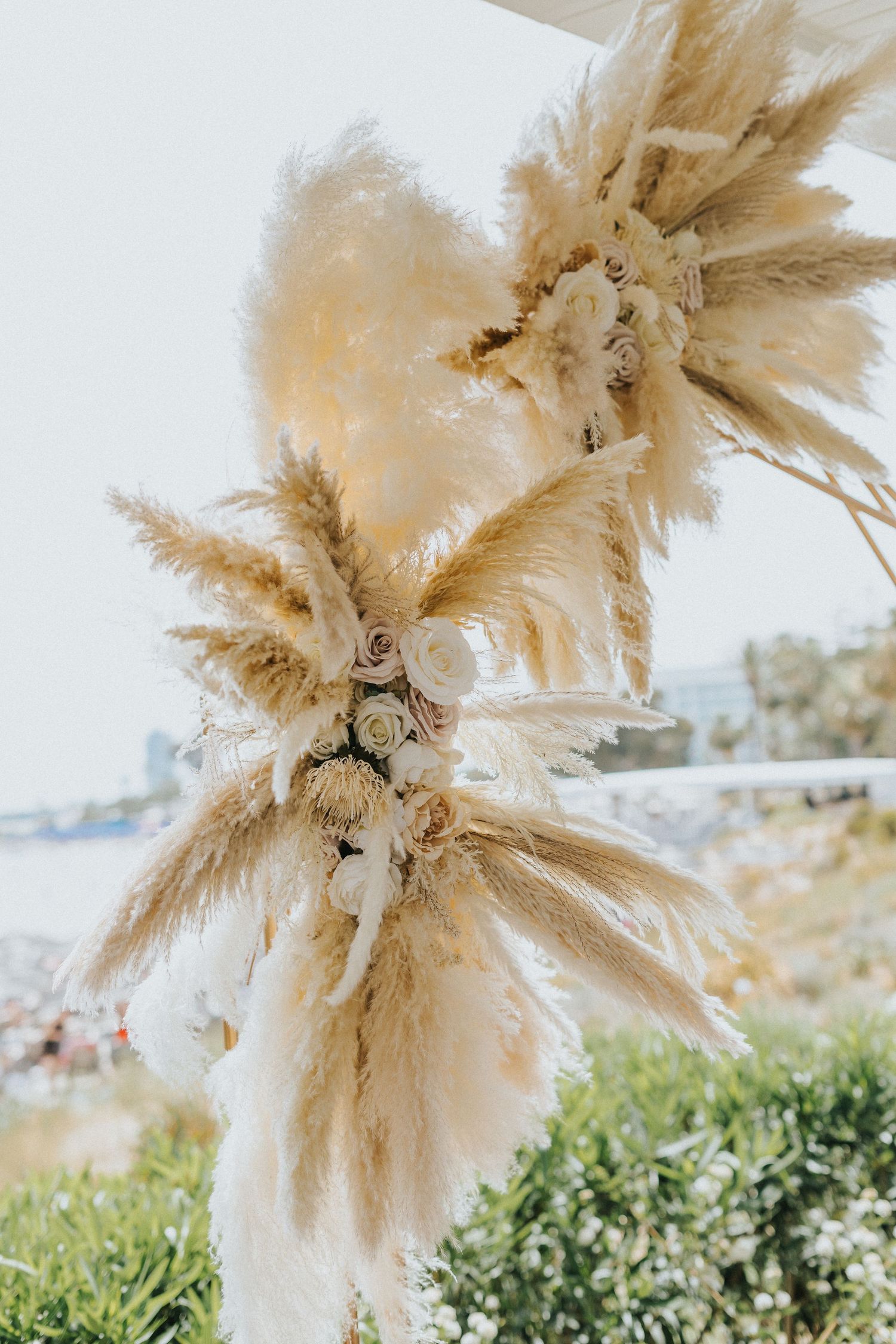 Artistic dried pampas grass floral arrangement in neutral tones against a white background.