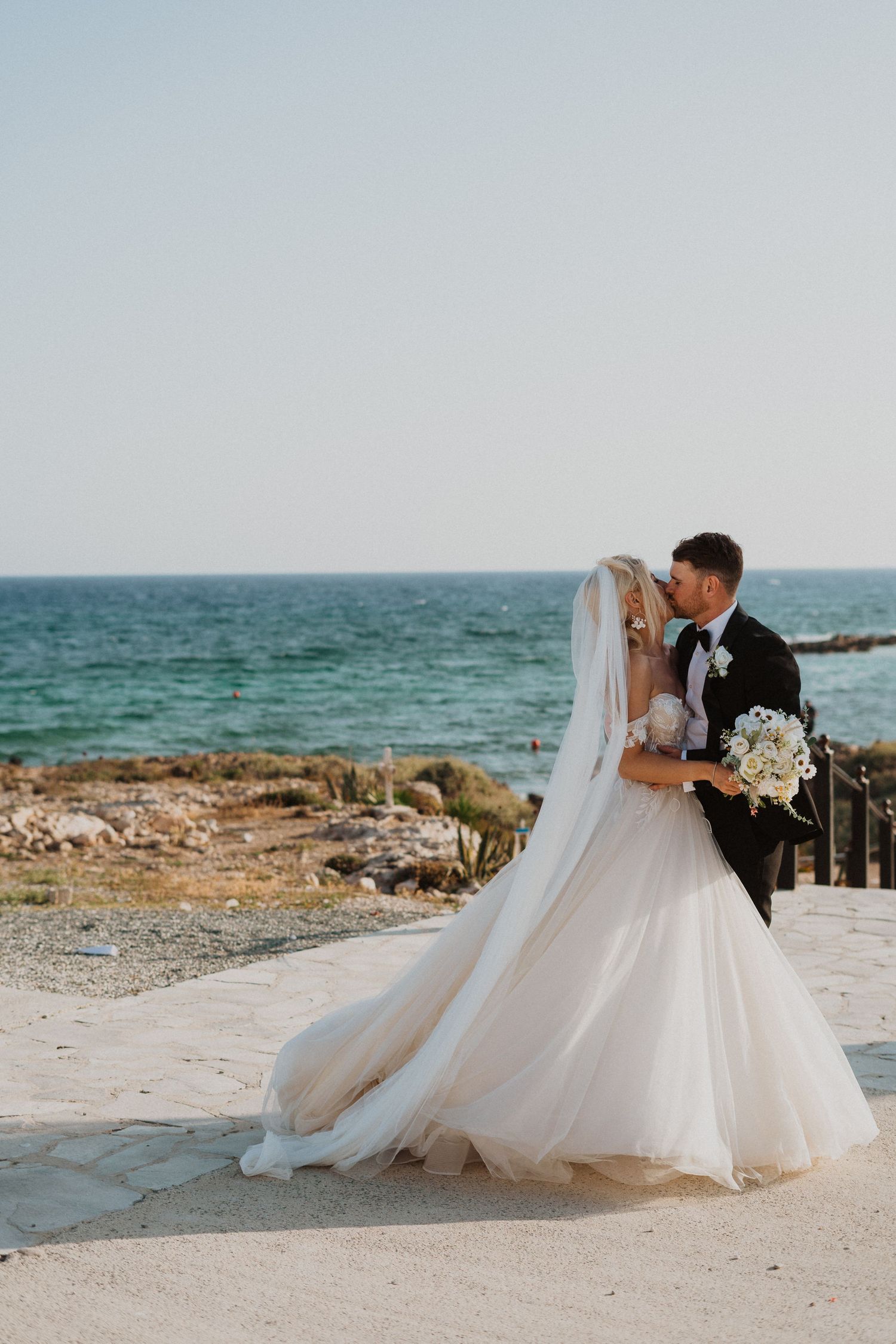 Wedding couple embraces during seaside photo session with turquoise waters.