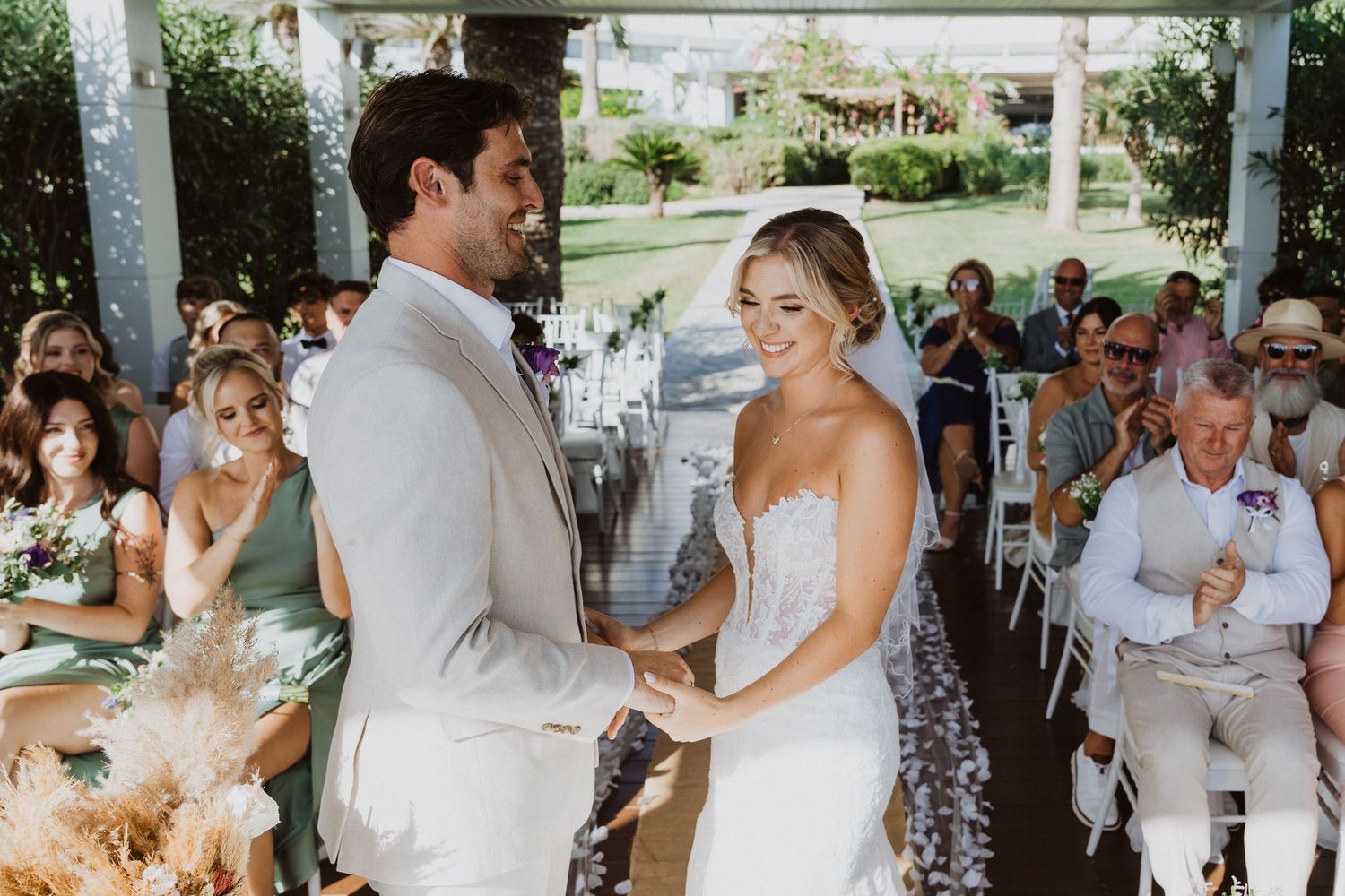 Wedding ceremony under covered pavilion with guests seated in garden setting.