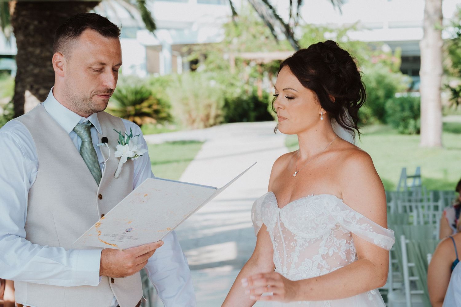 A couple shares a tender moment during their outdoor wedding ceremony under natural sunlight.