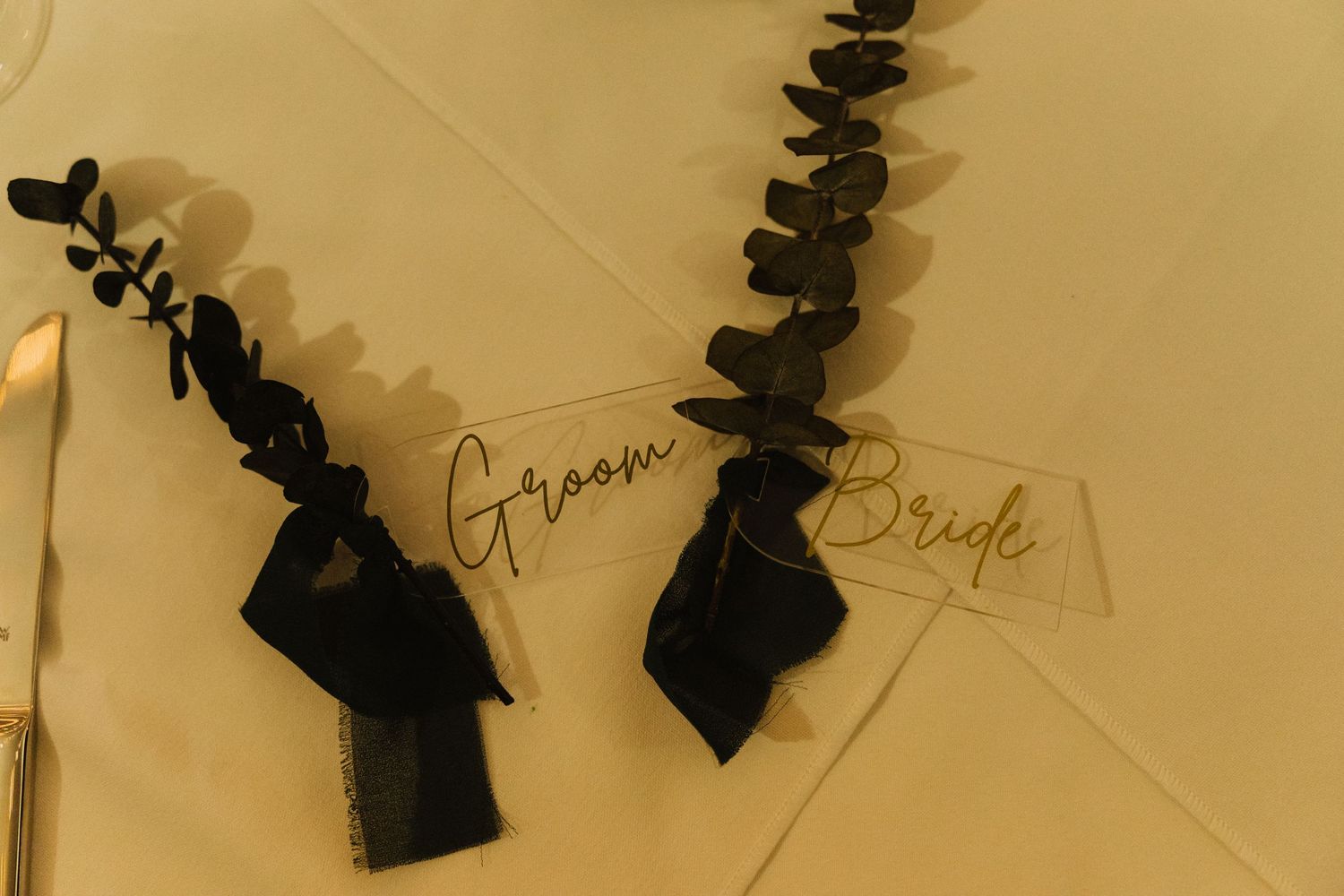 Black silhouette place cards for bride and groom with eucalyptus decorative elements.