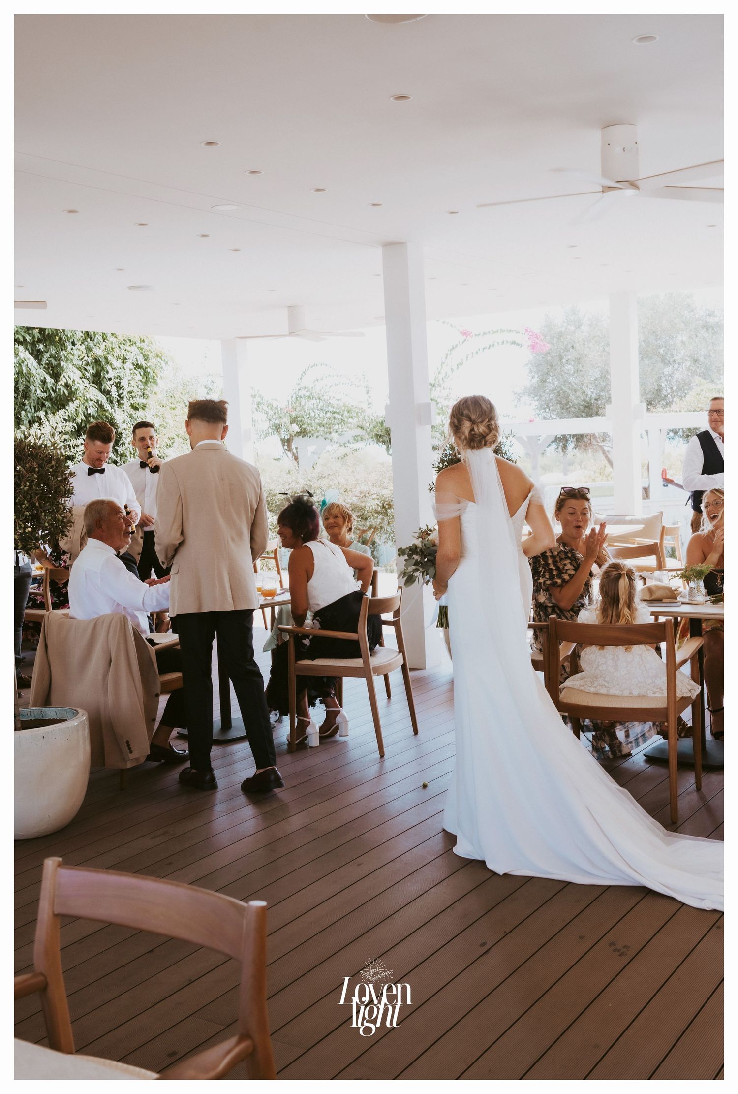 Wedding reception on an elegant covered deck with guests seated at tables.