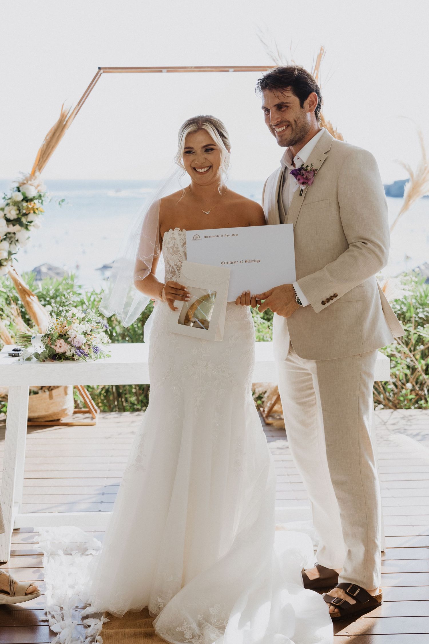 Newlyweds share a joyful moment while reviewing their wedding documents outdoors.