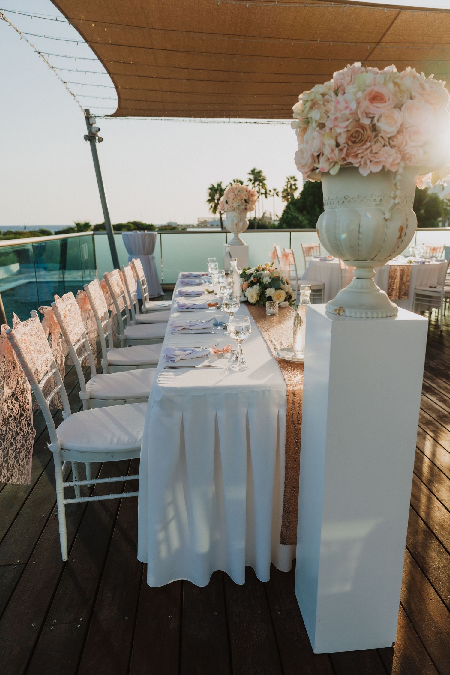 Wedding reception venue with white tablecloths and floral centerpieces under wooden beams.