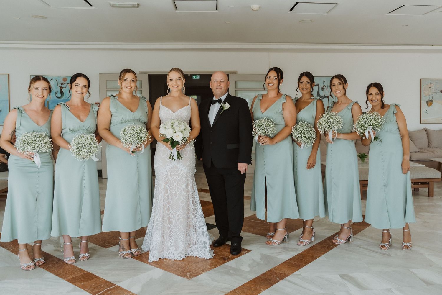 Wedding party poses in formal attire with bridesmaids wearing matching mint green dresses.