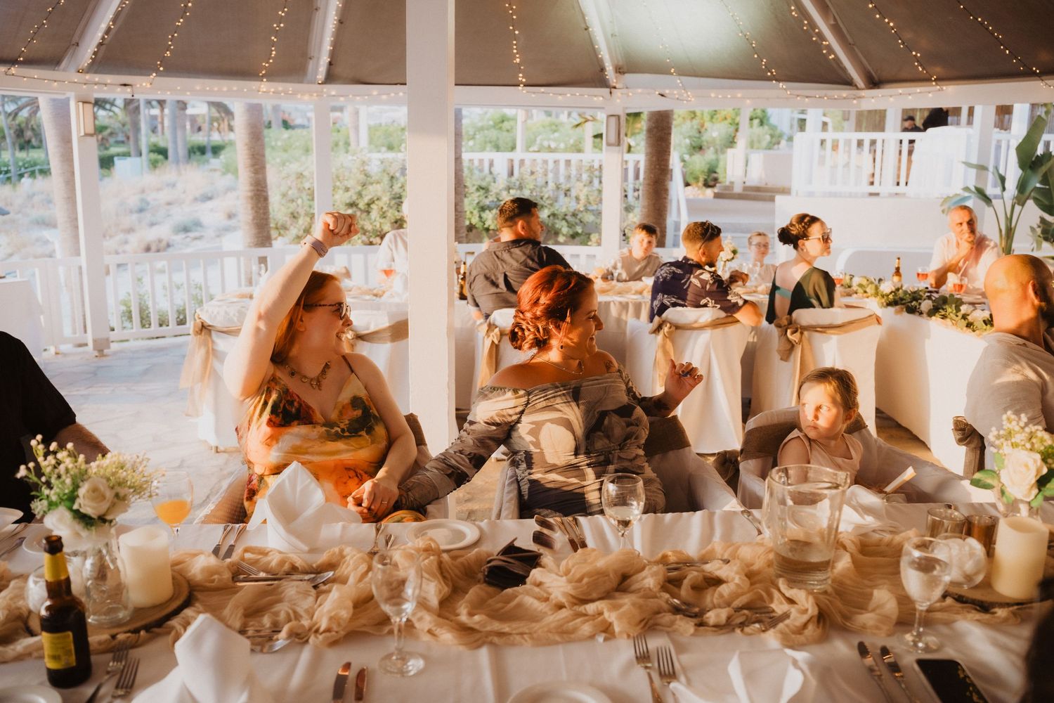 Wedding reception under tent with string lights and guests seated at decorated tables.