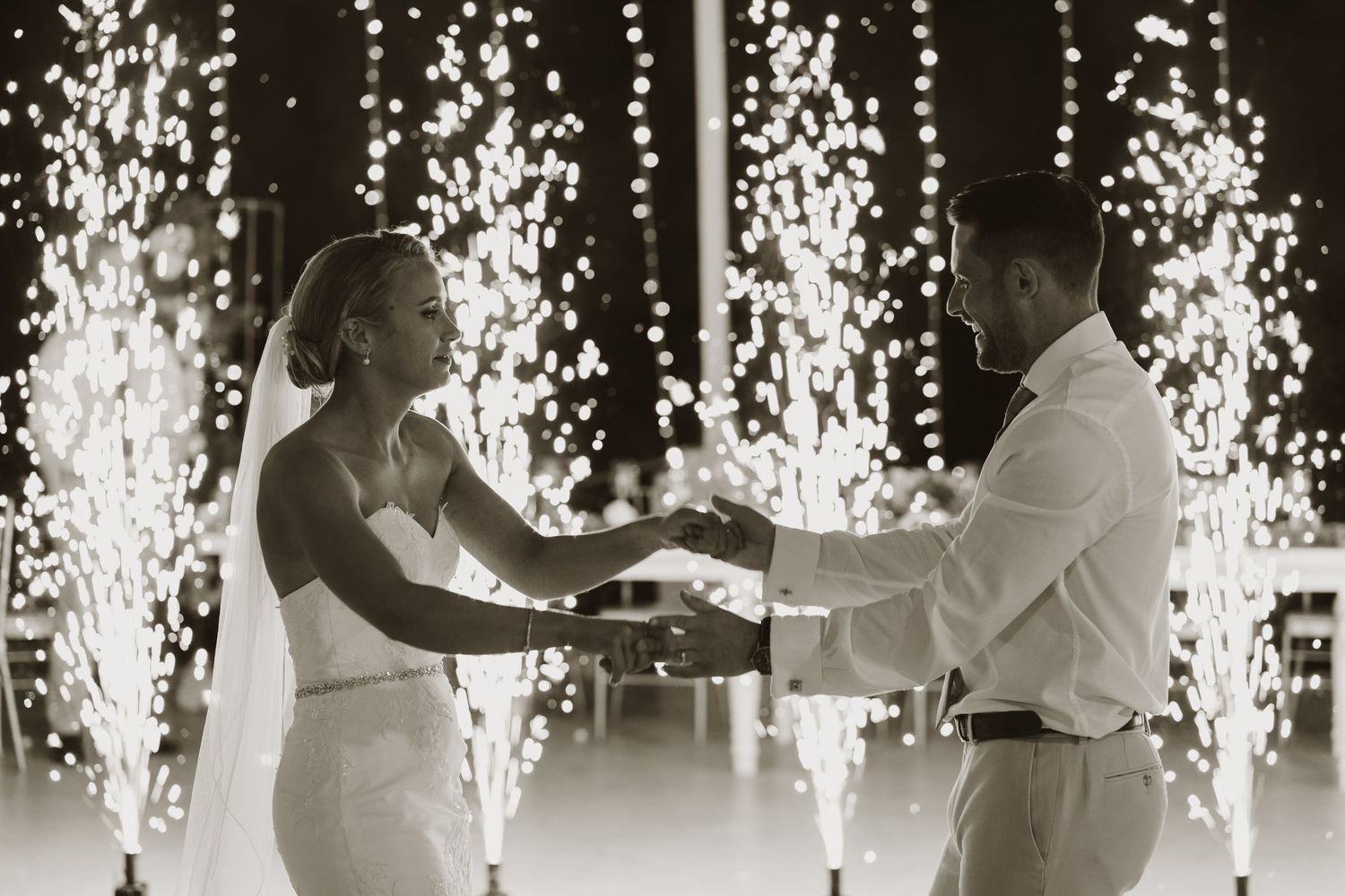 Black and white photo of couple's first dance with dramatic sparkler effects in background.