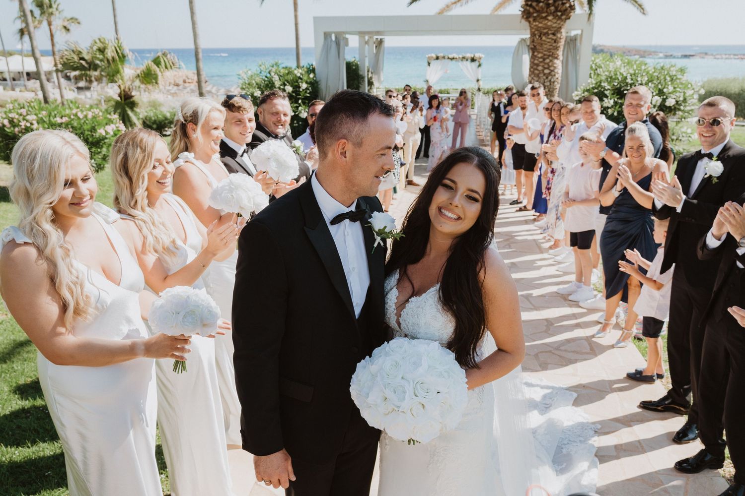 Beachside wedding celebration with guests in formal attire enjoying the outdoor festivities.