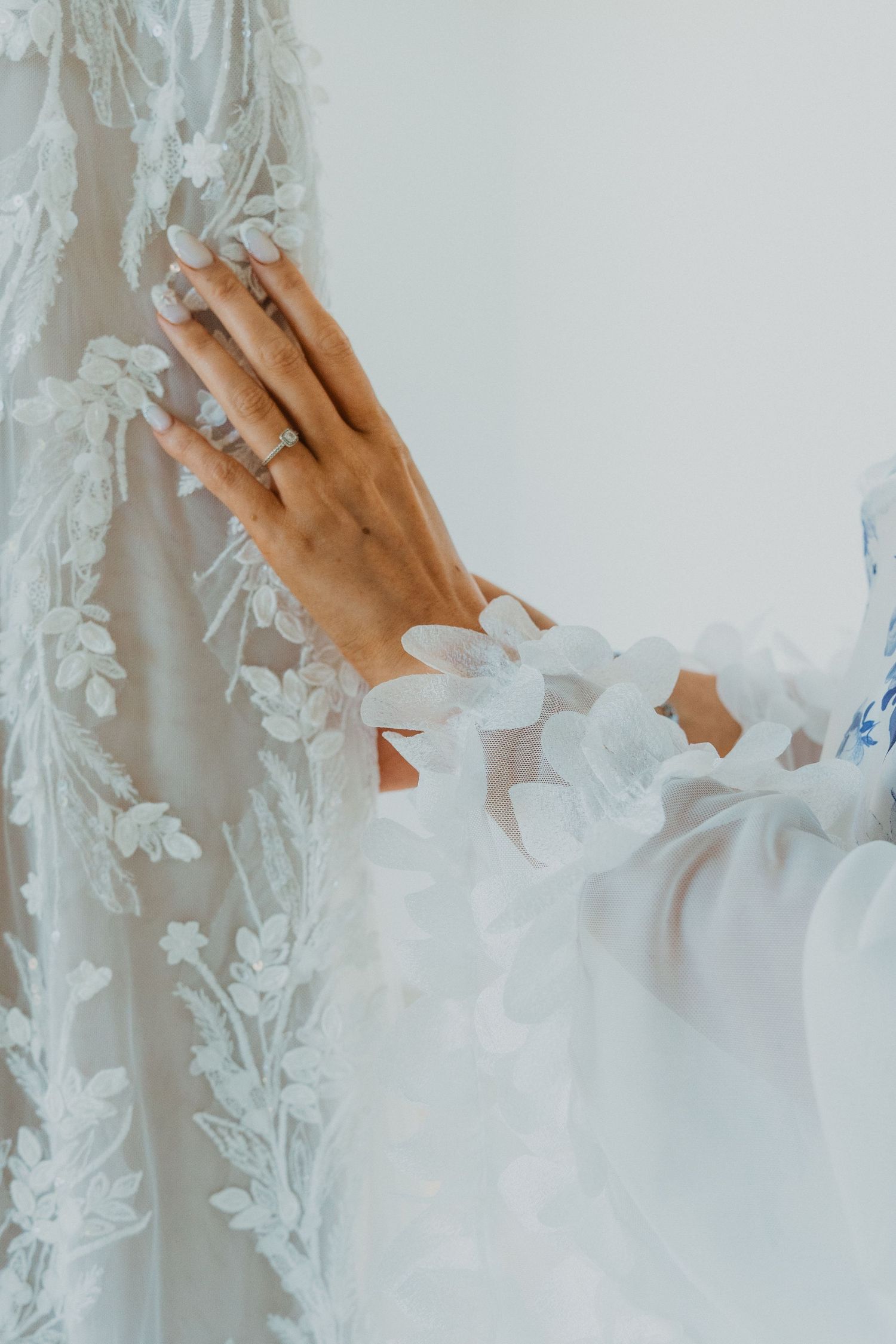 Close-up of delicate white lace wedding dress details with floral embroidery.