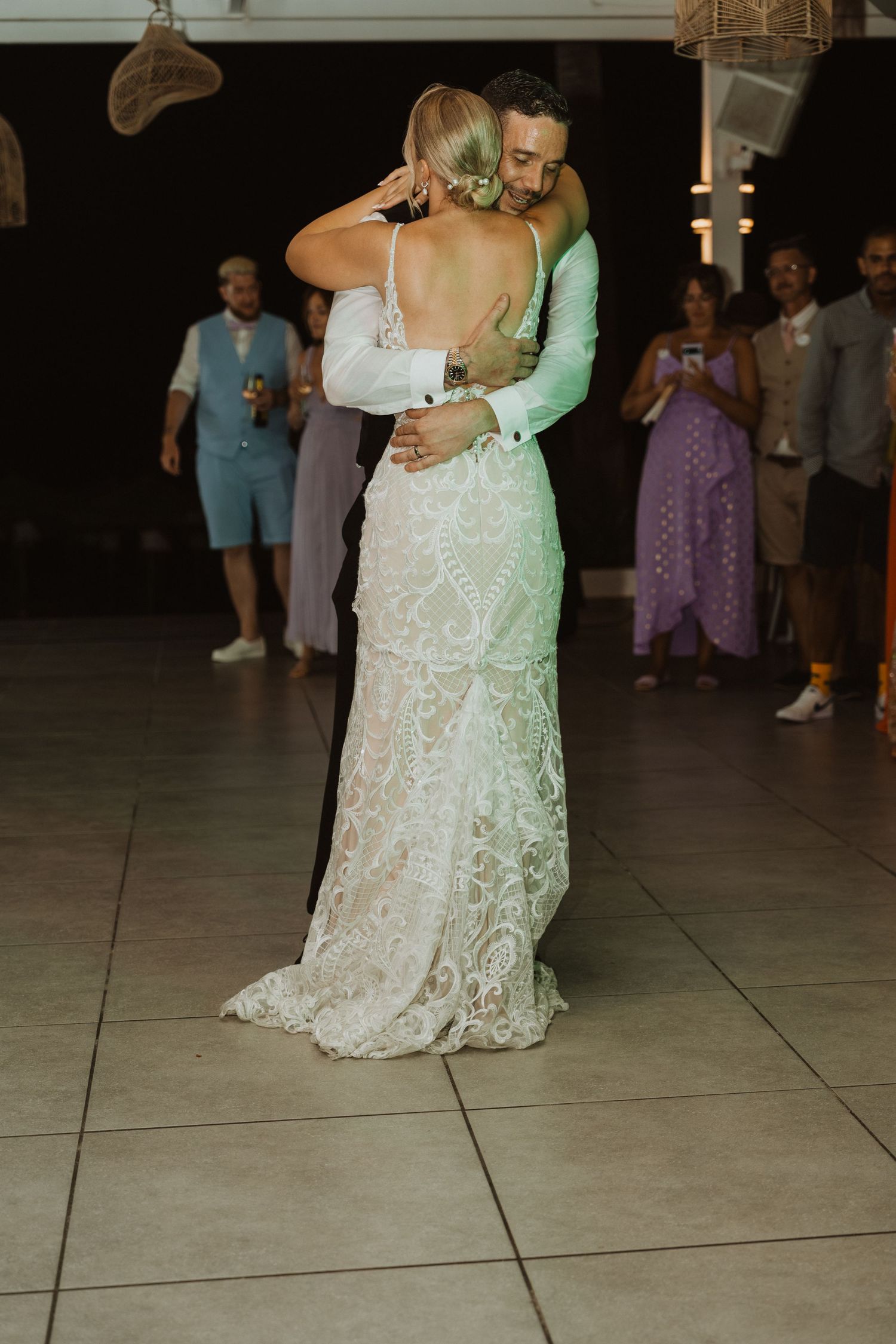 First dance moment captured on a tiled dance floor during an evening wedding reception.