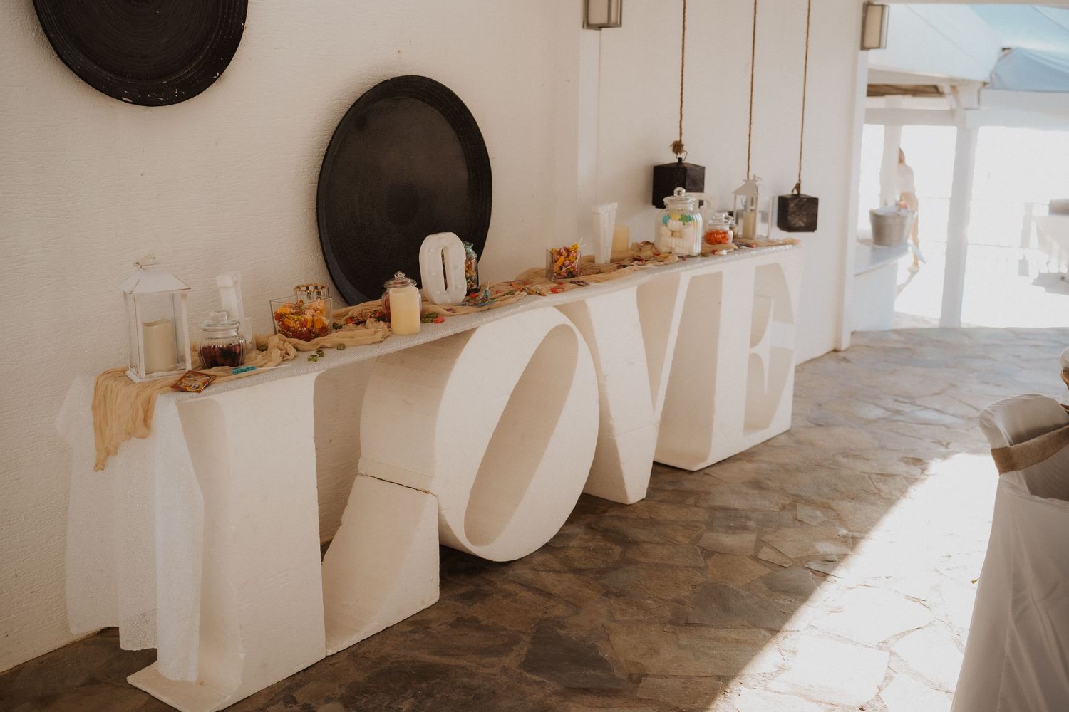 Large white 'LOVE' letters displayed on wooden floor against white wall with decorative accents.