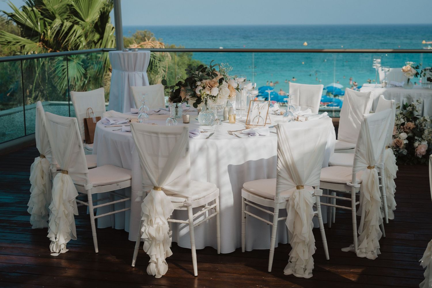 White and blush floral centerpieces with eucalyptus on mirrored bases at wedding reception.