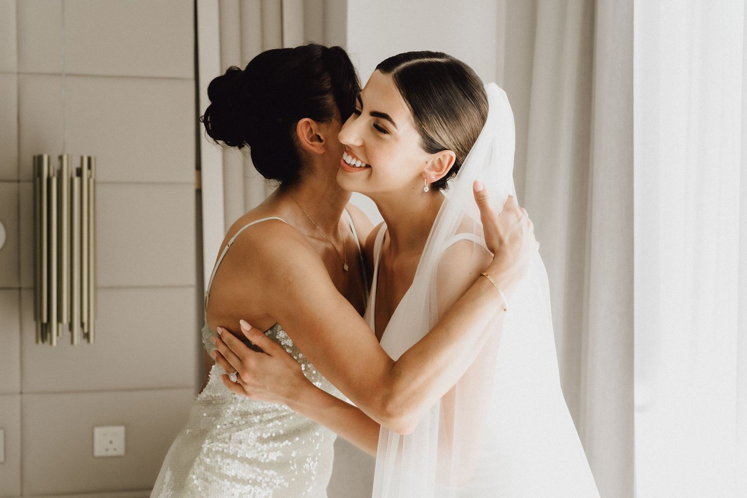 Two women embrace warmly during an emotional wedding day moment.