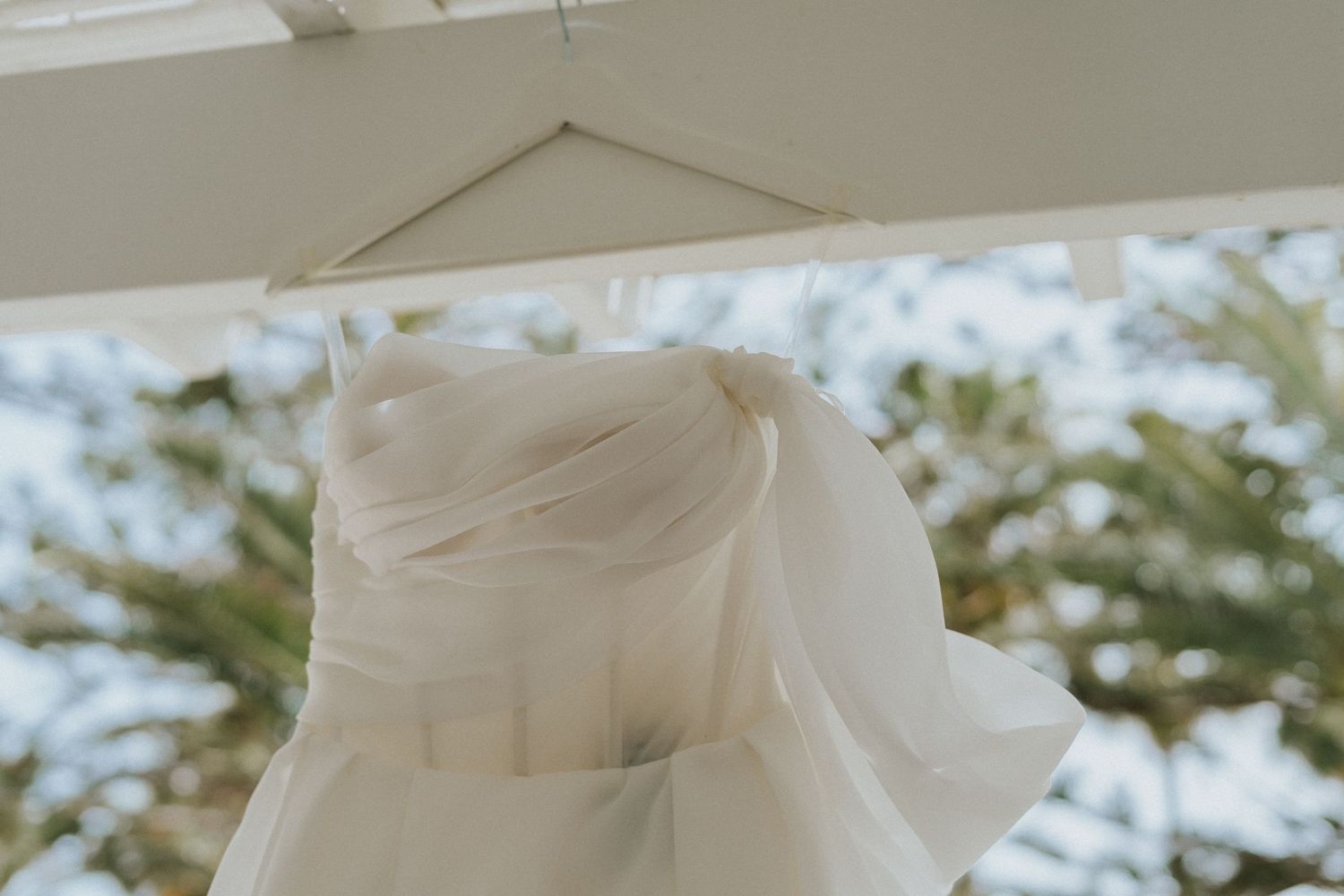 White wedding dress bodice detail hanging against natural outdoor lighting.