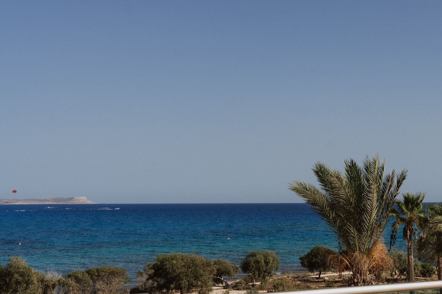 Panoramic view of a coastal resort with palm trees and turquoise ocean waters under clear blue skies.