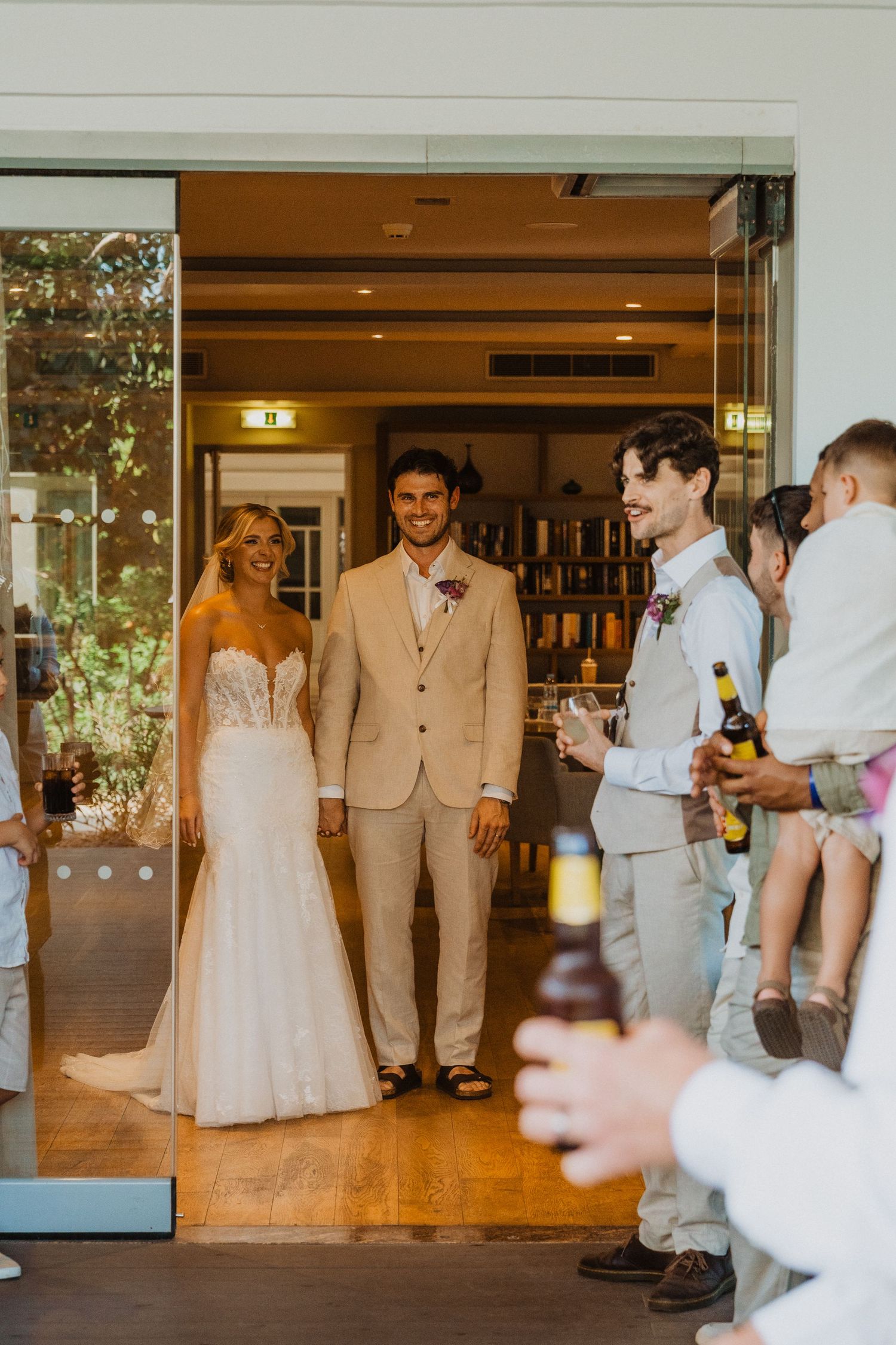 Wedding party gathers in reception venue wearing light colored formal attire.