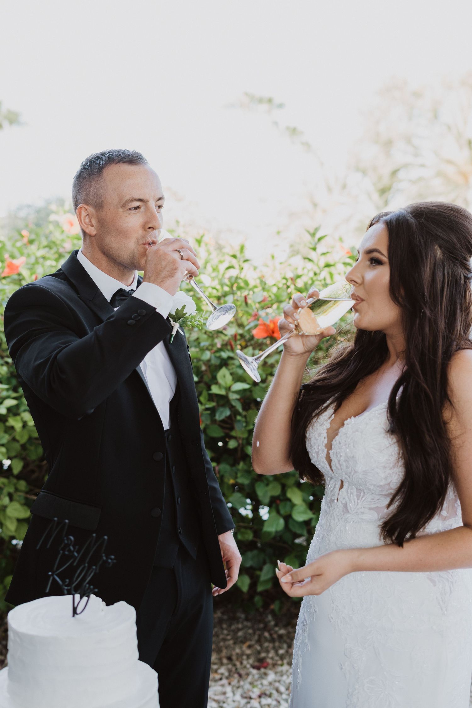 Bride and groom share champagne in a fun and candid moment outdoors.
