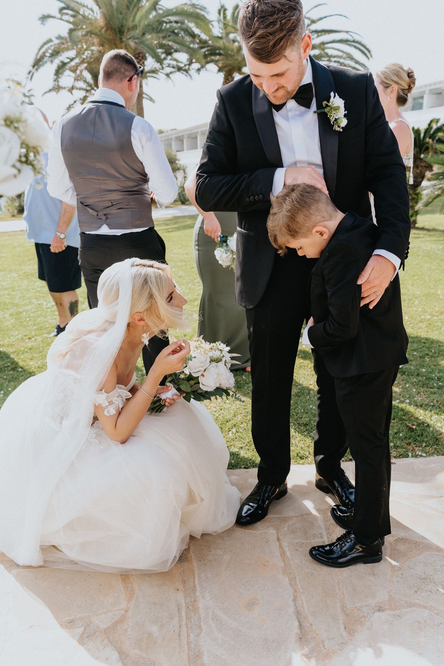 Sweet moment between wedding party members on stone patio during outdoor celebration.