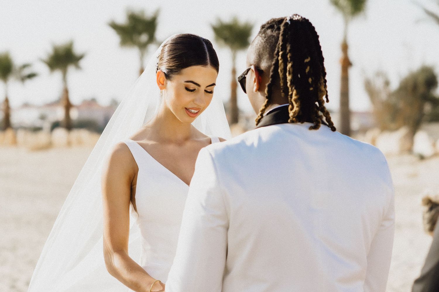 Intimate moment during seaside wedding ceremony with palm trees in background.