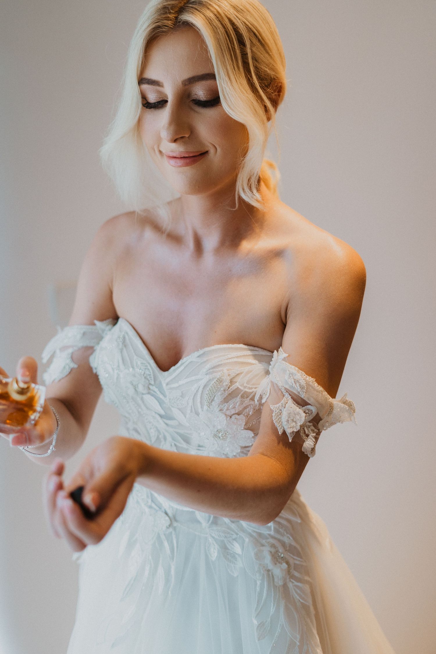 Ethereal portrait of a bride wearing an off-shoulder lace wedding gown in soft natural light.