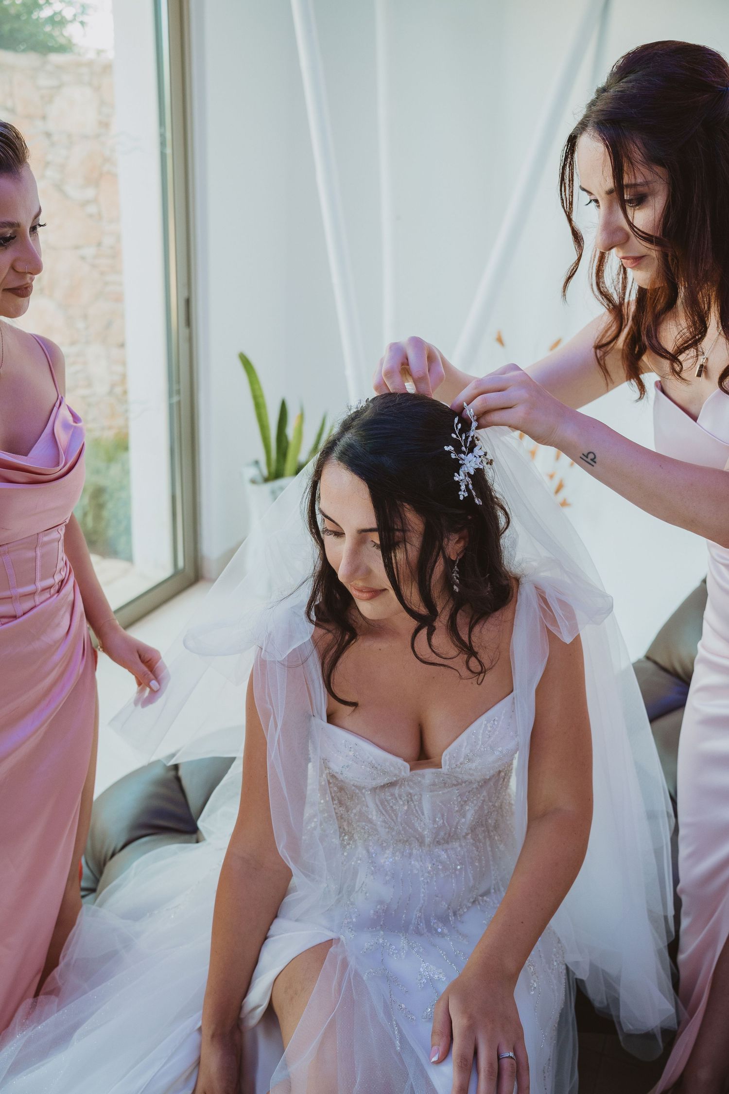 Bridesmaids help style the bride's hair while getting ready for the wedding ceremony.