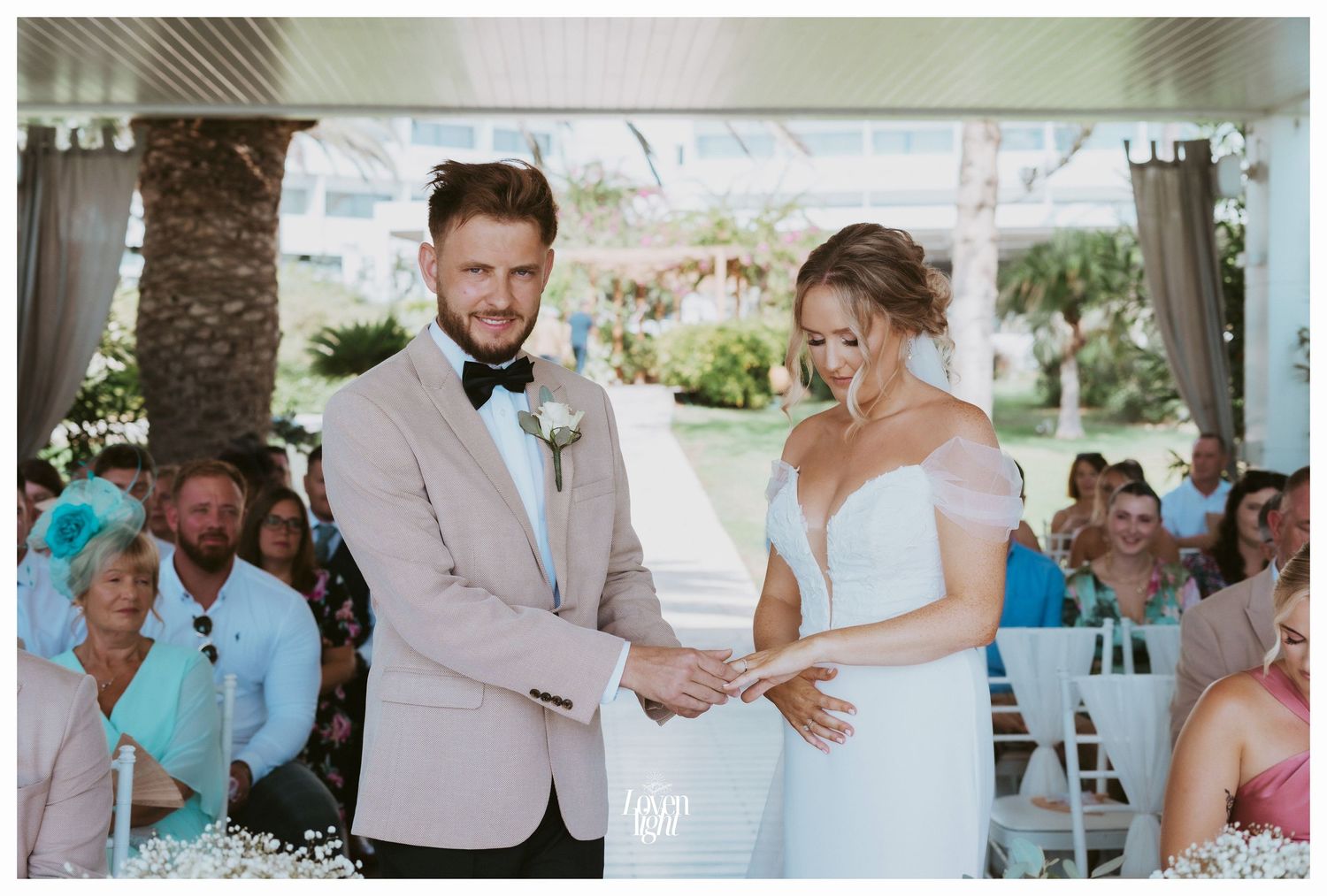 An emotional moment during a wedding ceremony with guests watching from white chairs.
